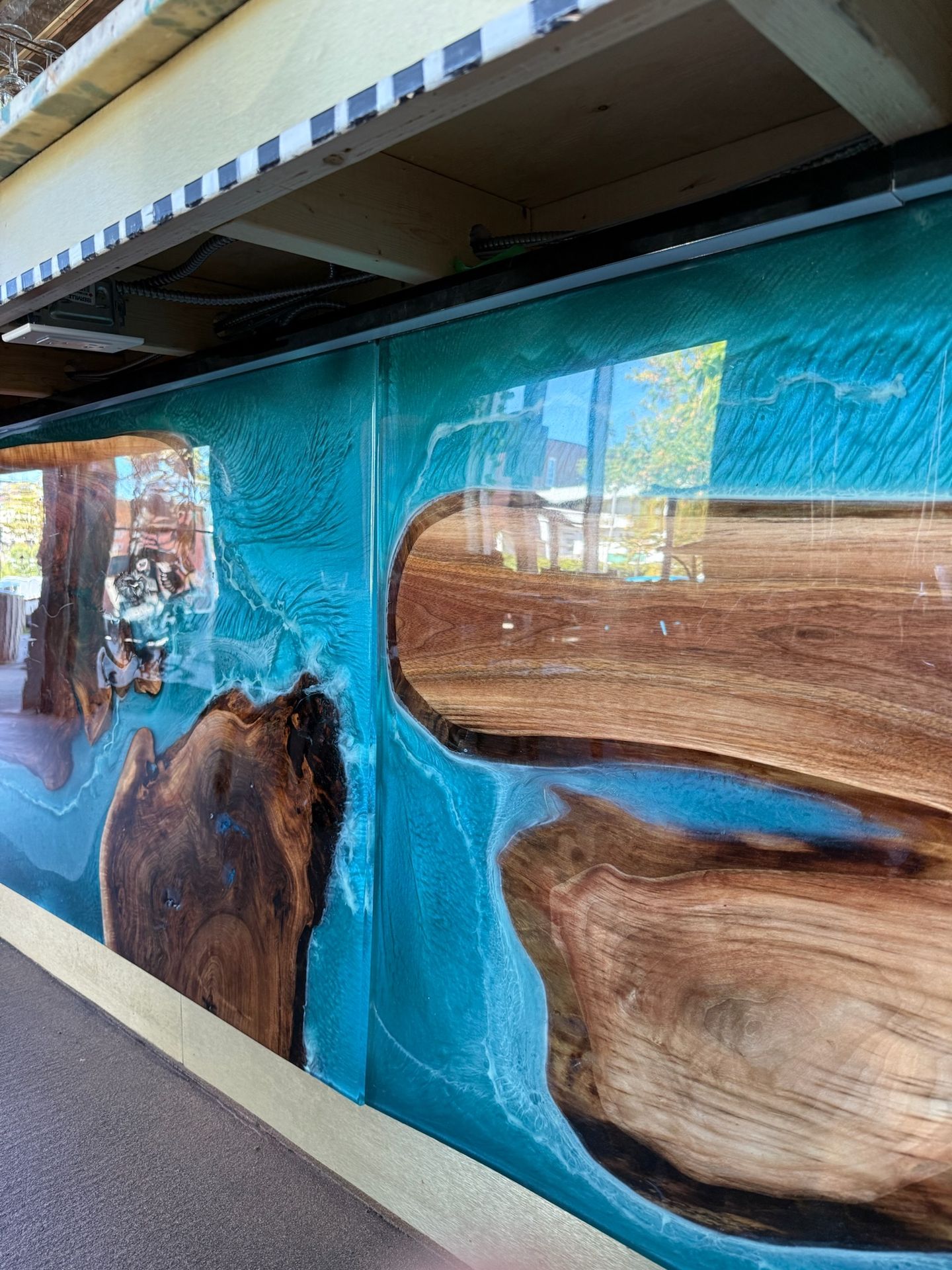 Détail de l’habillage de bar : noyer noir et résine époxy transparente bleu profond