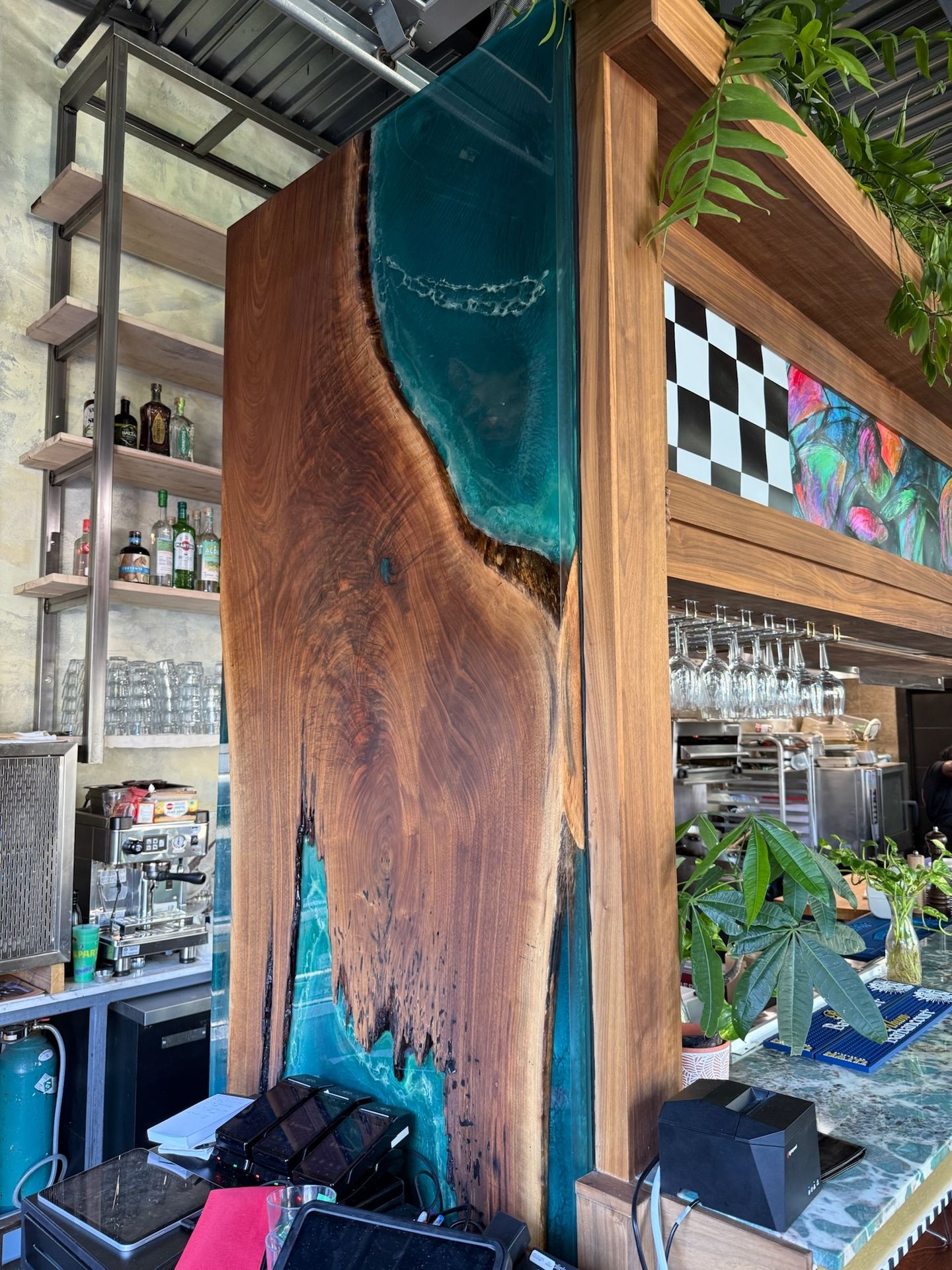 Relief sculptural d’une slab de noyer noir dépassant sur la façade de bar en époxy